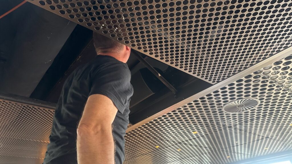 Ein Techniker schaut in die offene Deckenverkleidung.